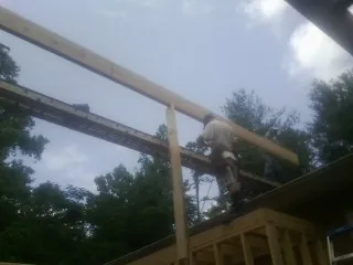 Carpenter setting a ridge beam over a new addition frame — Ice Dam Removal by Roofing Brothers in Somersworth