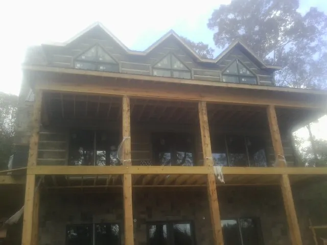 Dormers and porch framing on a large log home under construction — Roof Coating work by our crew in Somersworth