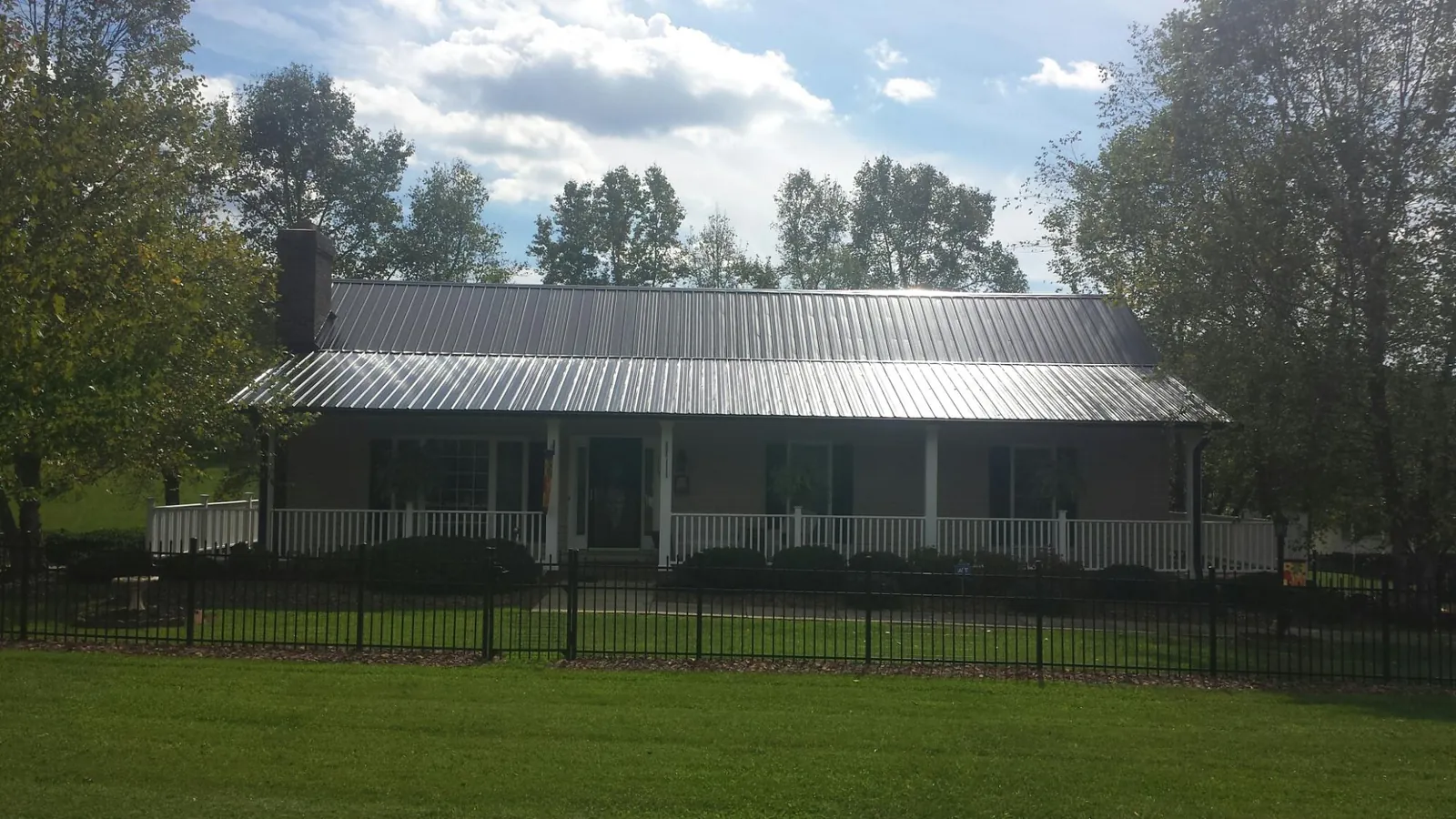 Gray metal roof on a brick ranch with a full width front porch — Gutter Guard Installation work by our crew in Somersworth