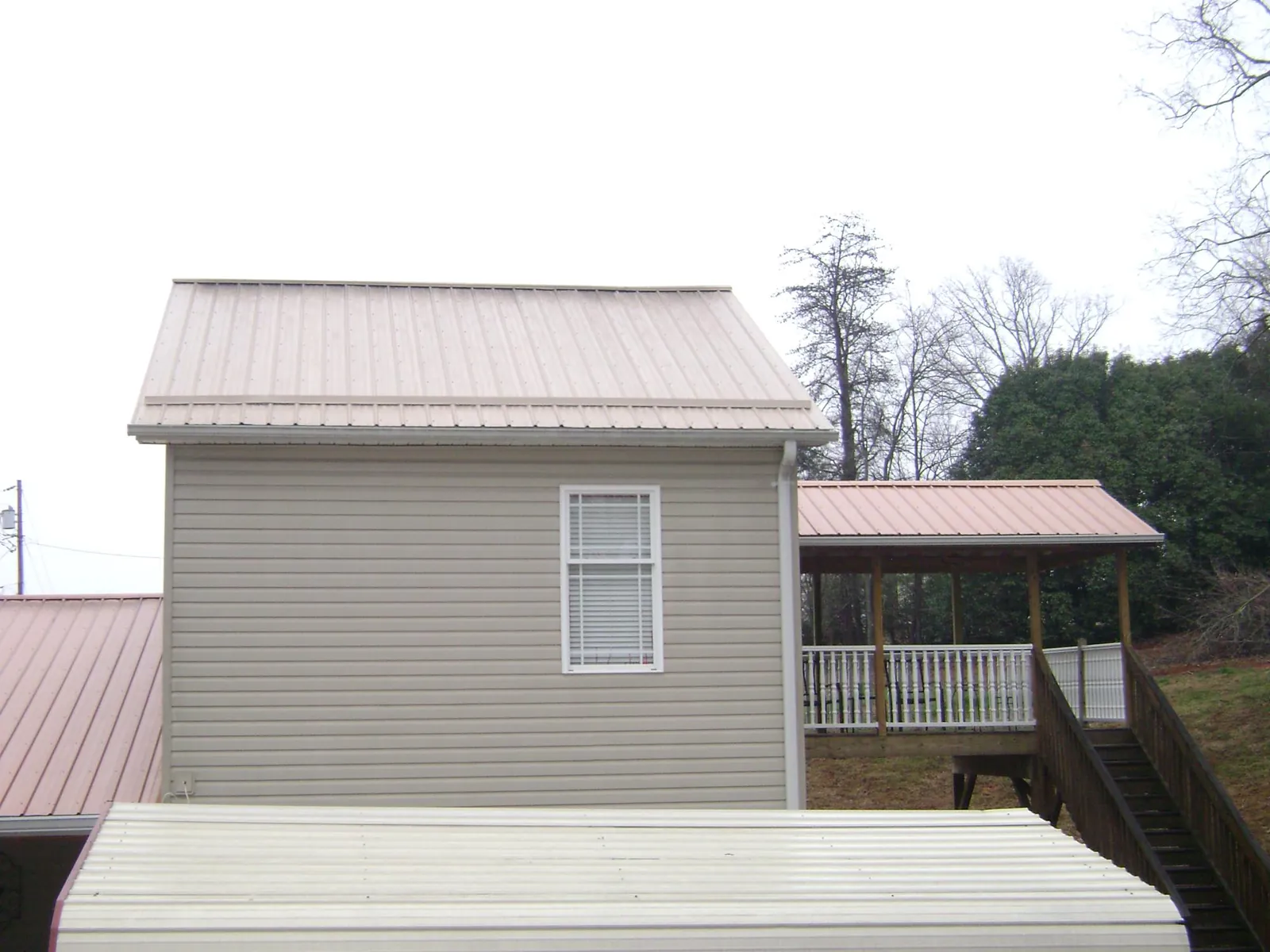 Tan metal roofs on a two story addition and attached porch, from a Roof Replacement job in Somersworth